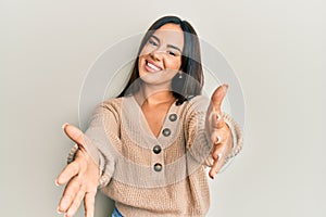 Young beautiful hispanic girl wearing casual winter sweater looking at the camera smiling with open arms for hug