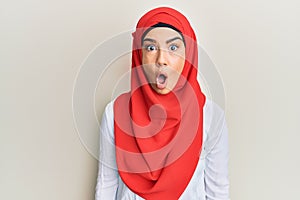 Young beautiful hispanic girl wearing traditional islamic hijab scarf afraid and shocked with surprise expression, fear and