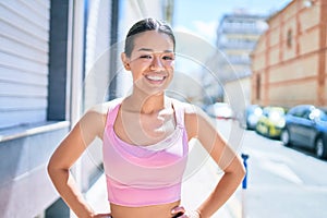 Young beautiful hispanic sporty woman wearing fitness outfit smiling happy and natural at the town