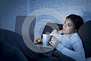 Young beautiful hispanic woman on bed at home working happy on laptop computer at night