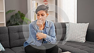 Young beautiful hispanic woman bitting nails stressed at home