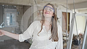 Young beautiful hispanic woman builder smiling confident taking out hardhat at construction site