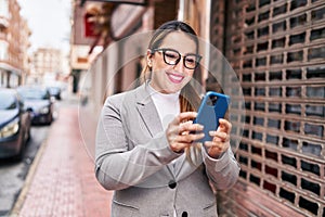 Young beautiful hispanic woman business worker smiling confident using smartphone at street