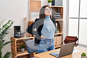 Young beautiful hispanic woman business worker suffering for backache at office