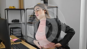 Young beautiful hispanic woman business worker suffering for backache using computer at office