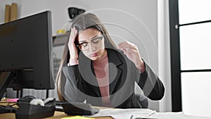 Young beautiful hispanic woman business worker using computer and calculator stressed at office
