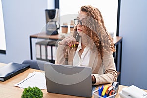 Young beautiful hispanic woman business worker using laptop with serious expression at office