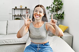 Young beautiful hispanic woman communicate with deaf language sitting on sofa at home