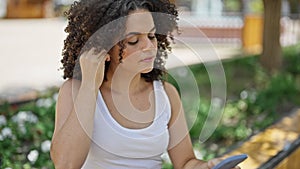 Young beautiful hispanic woman dancing listening to music on smartphone at park