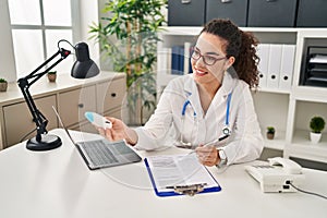 Young beautiful hispanic woman doctor smiling confident holding nasal treatment at clinic