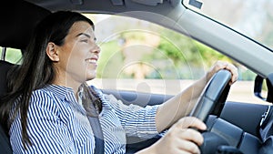 Young beautiful hispanic woman driving a car smiling on the road