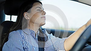Young beautiful hispanic woman driving a car smiling on the road