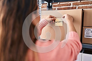 Young beautiful hispanic woman ecommerce business worker putting returned reminder paper on package at office