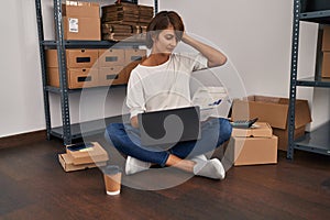 Young beautiful hispanic woman ecommerce business worker reading document with serius expression at office photo