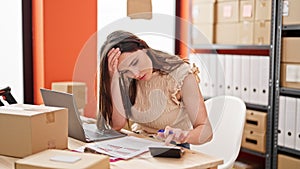 Young beautiful hispanic woman ecommerce business worker stressed doing account at office