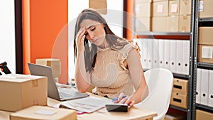 Young beautiful hispanic woman ecommerce business worker stressed doing account at office