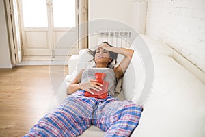 Young beautiful hispanic woman holding hot water bottle against belly suffering menstrual period pain