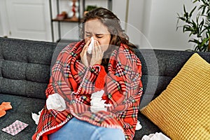 Young beautiful hispanic woman ill using napkin at home