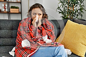 Young beautiful hispanic woman ill using napkin at home