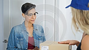 Young beautiful hispanic woman opening door receiving package at home