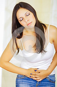 Young beautiful hispanic woman in painful expression touching her belly, suffering menstrual period pain, female health