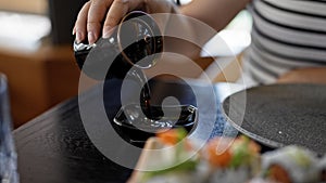 Young beautiful hispanic woman pouring soja sauce at the restaurant