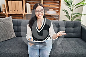 Young beautiful hispanic woman psychologist smiling confident speaking at psychology clinic