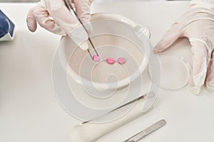 Young beautiful hispanic woman scientist holding pill at laboratory