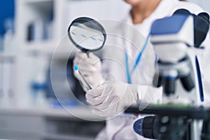 Young beautiful hispanic woman scientist looking test tube with loupe at laboratory