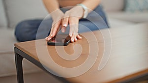 Young beautiful hispanic woman sitting on sofa holding smartphone at park