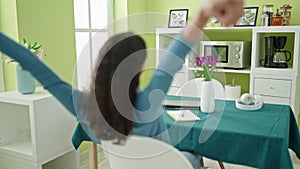 Young beautiful hispanic woman sitting on the table backwards view writing on notebook at street