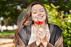 Young beautiful hispanic woman smiling confident holding flower at park