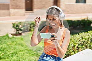 Young beautiful hispanic woman smiling confident playing video game at park