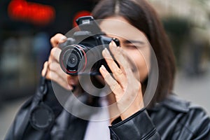 Young beautiful hispanic woman smiling confident using professional camera at street