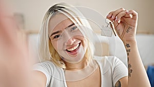 Young beautiful hispanic woman smiling holding new house keys taking selfie at new home