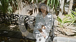 Young beautiful hispanic woman smiling sitting on a bench at park