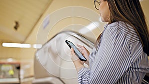 Young beautiful hispanic woman standing on escalator using smartphone in subway station of Madrid