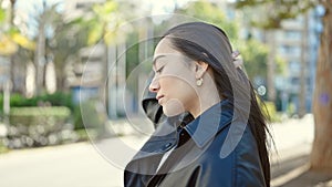 Young beautiful hispanic woman standing with serious expression combing hair with hand at park