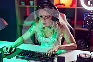 Young beautiful hispanic woman streamer playing video game using computer at gaming room