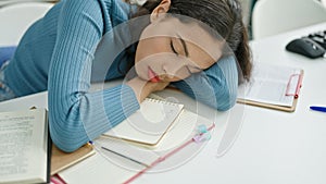 Young beautiful hispanic woman student sleeping on the desk at university classroom