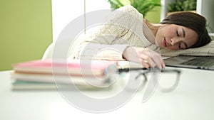 Young beautiful hispanic woman student sleeping on table at home