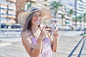 Young beautiful hispanic woman tourist using vintage camera at street