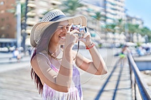 Young beautiful hispanic woman tourist using vintage camera at street