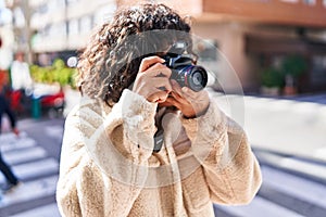 Young beautiful hispanic woman using professional camera at street