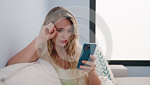 Young beautiful hispanic woman using smartphone with sadness expression at home