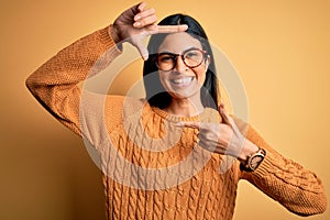 Young beautiful hispanic woman wearing glasses over yellow isolated background smiling making frame with hands and fingers with