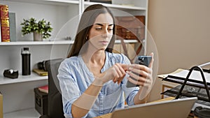 Young and beautiful hispanic woman working hard at the office, typing and texting professionally on her laptop and phone