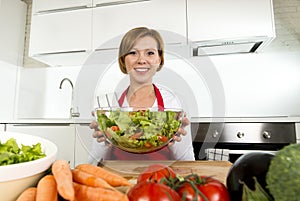 Young beautiful home cook woman at modern kitchen preparing vegetable salad bowl smiling happy