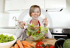 Young beautiful home cook woman at modern kitchen preparing vegetable salad bowl smiling happy