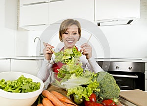 Young beautiful home cook woman at modern kitchen preparing vegetable salad bowl smiling happy